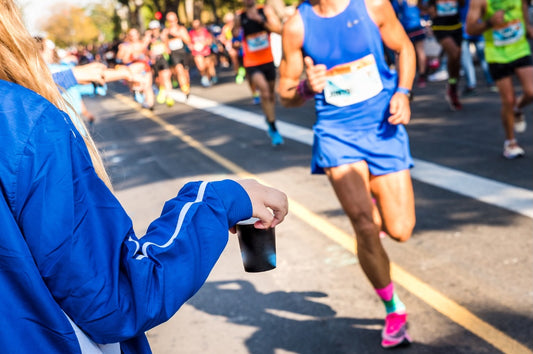 athlete grabbing fluids from marathon aid station 